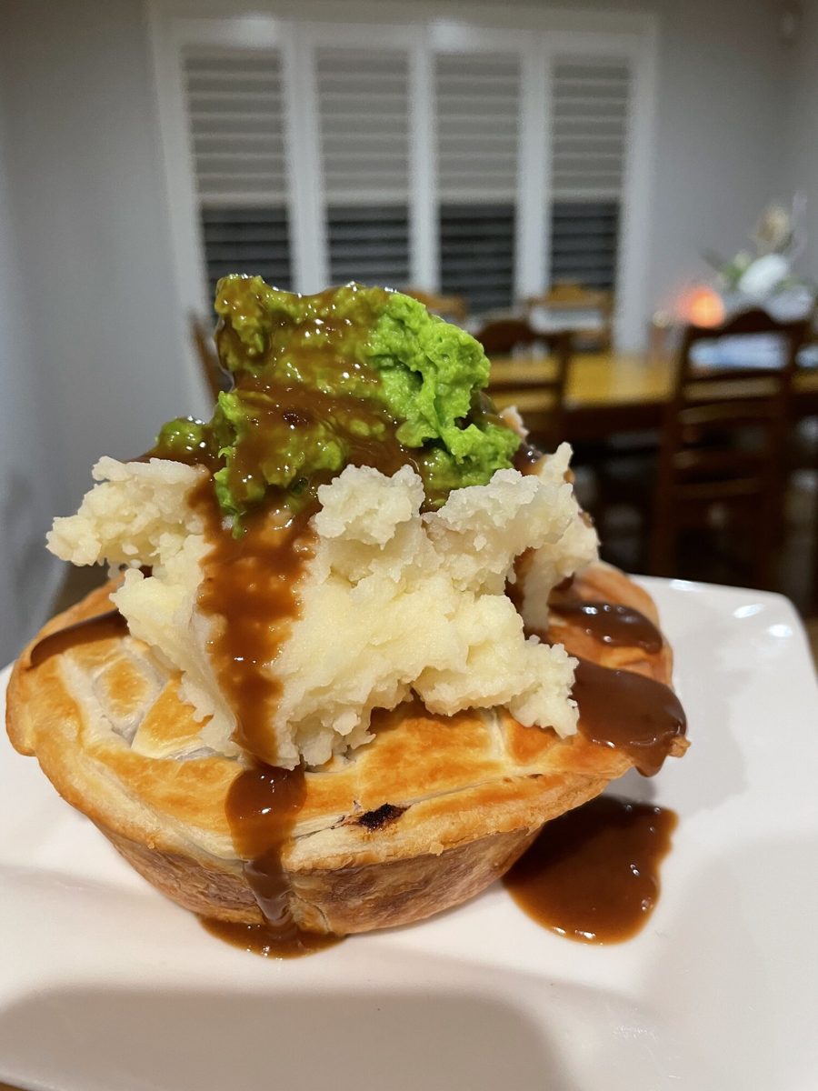 A homemade pie topped with mash, mushy peas and gravy